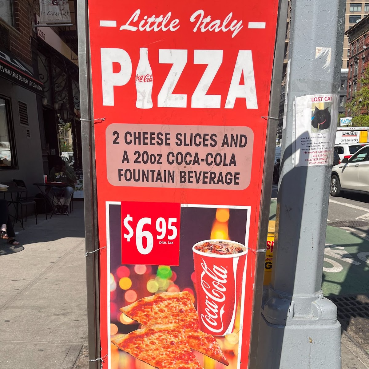 This photo shows a sign from Little Italy Pizza, advertising a lunch special. The advertisement has two slices of cheese pizza and a Coca Cola beverage on the cover.