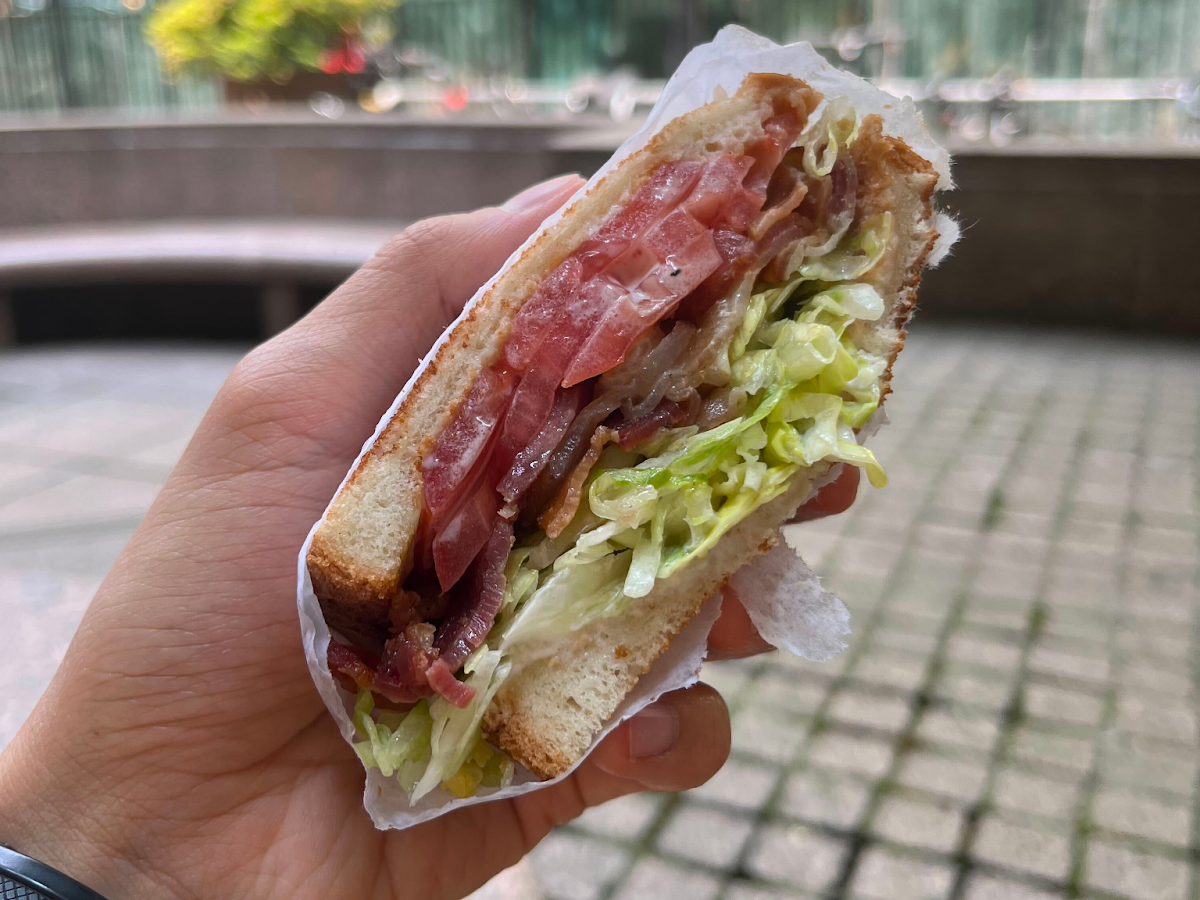 This photo shows a hand holding a sandwich from Hunter Delicatessen. The sandwich is broken in half, showing what is inside. It consists of two slices of toasted white bread with slices of turkey meat and lettuce in between.